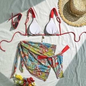 Three-piece paisley bikini set with red halter top and matching sarong on white fabric