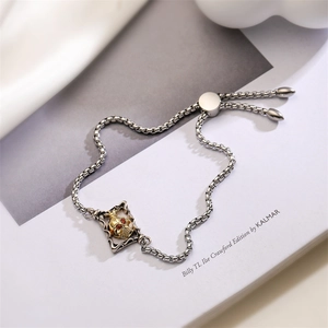 Macro shot of silver square link bracelet with gold skull charm and red zircon eyes