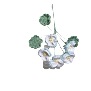 Handmade crochet pansy bouquet in white and blue yarn with green leaves on white background