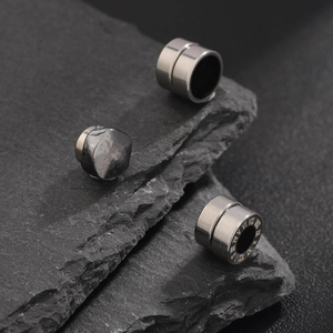 Polished titanium steel magnetic clip earrings with Roman numerals on stone background