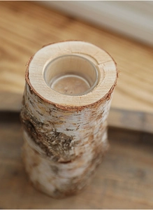 Detail showing natural birch wood texture and glass candle holder cup on the wooden base