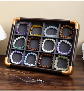 Detail of 12-grid walnut wood jewelry tray with gold corners and velvet lining slots