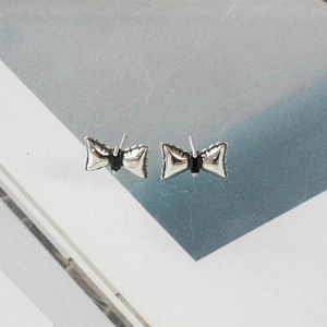 Minimalist 925 sterling silver bow earrings with black zircon accents on a gray background