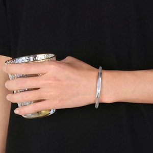 Detailed close-up of woven stainless steel mesh bracelet on a wrist holding a glass