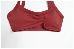 Détail d'un soutien-gorge de yoga rouge foncé avec design torsadé et larges bretelles