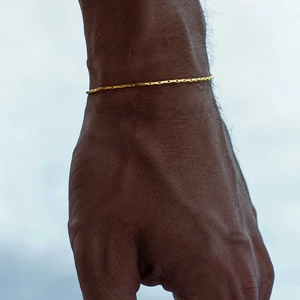 Gros plan d'un bracelet fin à chaîne câblée dorée porté délicatement au poignet