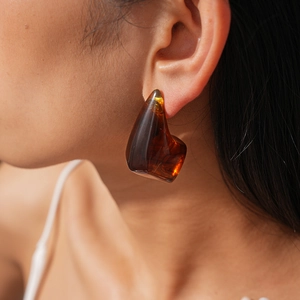 Macro side view of an irregular amber resin geometric earring on a model