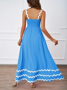 Detail view of the back of a blue summer dress showing white wavy trim and fabric texture
