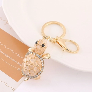 Macro detail of champagne turtle keychain with opal stones and sparkling rhinestones