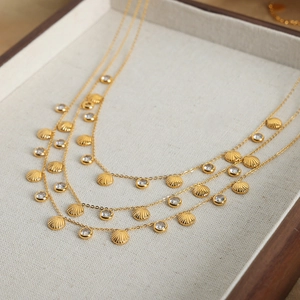 Gold-plated ocean shell necklace with zircon accents on a beige linen display tray