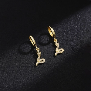 Detailed view of snake-shaped golden drop earrings with sparkling pavé crystals