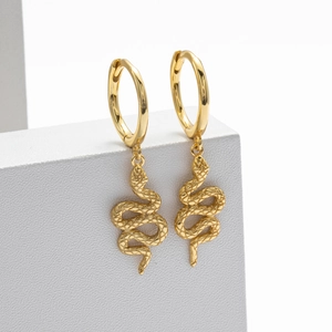 Macro shot of gold snake drop earrings featuring detailed scales and hoop clasp design