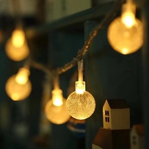 Close-up of frosted LED globe string lights with warm yellow glow and bubble textures