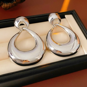 Macro shot of silver polished water drop earrings inside a premium black jewelry box