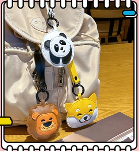 Cute leather panda, lion, and shiba inu charms hanging on a beige backpack