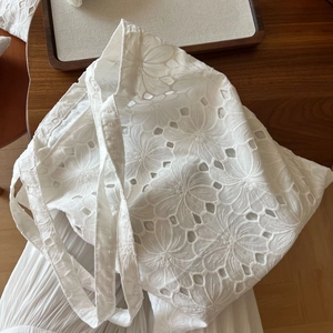 Detailed view of floral eyelet embroidery on a white cotton canvas tote bag surface