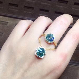 Close-up of blue-green high carbon diamond ring and pendant set on hand