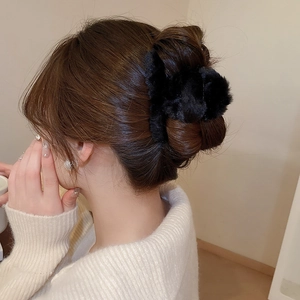 Detail view of a soft black plush cloud-shaped hair claw clip on a woman's bun hairstyle
