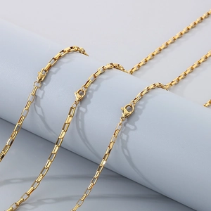 Detailed view of multiple gold-plated stainless steel box chains on a grey display stand