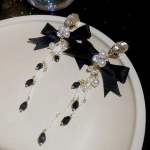 Detailed view of luxury bowknot earrings with pearl tassels and crystal on a ceramic tray