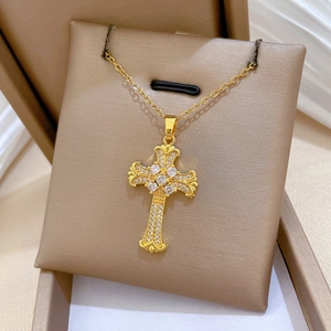Dettaglio ravvicinato di una collana con ciondolo a croce dorata e zirconi brillanti