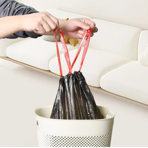 Strong black drawstring trash bags with red handles shown in a home living room setting