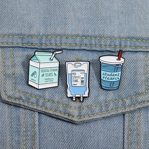 Close-up of creative enamel pins featuring medical student tears and milk carton on denim