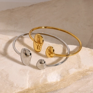Gros plan de bracelets ouverts style lave en or et argent sur une base de pierre brute
