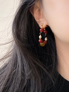 Close-up of ethnic style beaded hoop earrings with agate pearls and golden beads