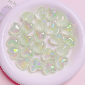 Macro shot of shimmering heart-shaped resin beads for DIY jewelry in green iridescent finish