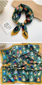 Detail view of a green silk scarf with colorful cat patterns and yellow edges