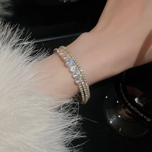 Detail of luxurious multi-layered gold bracelet with sparkling cubic zirconia on a wrist