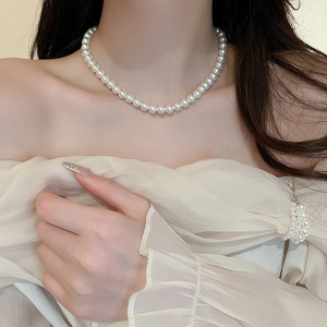 Close-up of elegant single strand white pearl necklace worn on a model's neck
