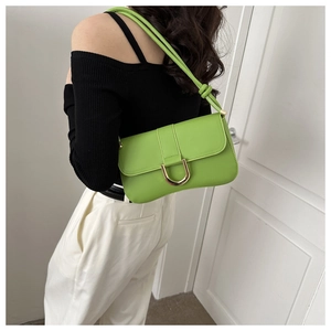 Detail view of bright green baguette bag with golden D-buckle and shoulder strap on model
