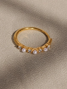 Close-up of golden ring set with three pearls and four crystal zircon stones