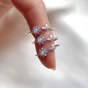 Silver flower and butterfly open rings with opal accents shown in a stacked style