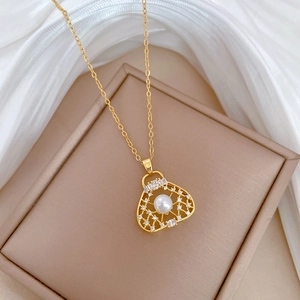 Macro detail of gold hollow pendant with pearl and crystals on a beige jewelry box