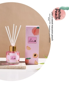 Close-up of white peach reed diffuser set with glass bottle and pink packaging box