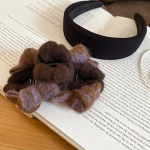Detail of a brown flocking bow claw clip and black padded headband on an open book