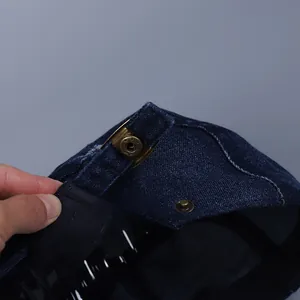 Detail of vintage bronze snap button on a dark blue denim flat cap with texture