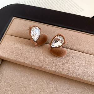 Macro view of brown flocked heart earring with pear-shaped crystal in a jewelry box