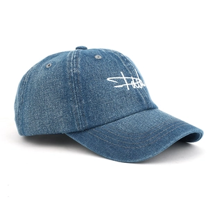 Close-up of blue denim baseball cap featuring white cursive embroidery and premium stitching