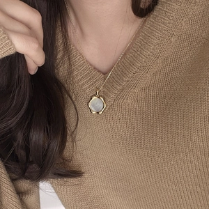 Macro detail of a 925 silver bamboo chain necklace with a hexagonal shell pendant on model