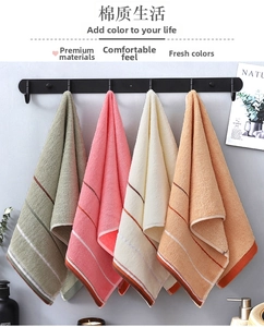 Detailed view of four cotton towels in gray, pink, beige, and orange with striped borders