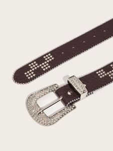 Macro shot of rhinestone-studded buckle and embossed leather texture on punk style belt