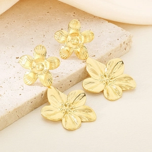 Detailed macro view of 18K gold-plated stainless steel pearl flower earrings on stone