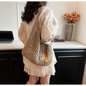 Close-up of khaki woven beach tote bag featuring hollow-out knit design and yellow tassel
