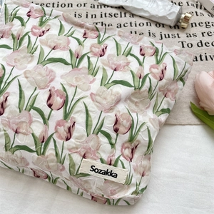 Détail du tissu jacquard à tulipes roses et étiquette de marque sur la trousse de maquillage