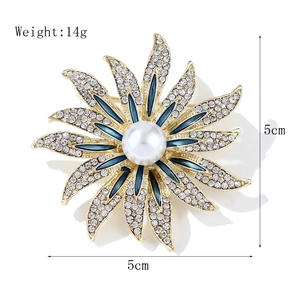 Golden sunflower brooch with white crystals, blue enamel, and a pearl centerpiece