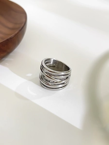 Detailed macro view of silver multi-layer intertwined wire mesh ring on white surface